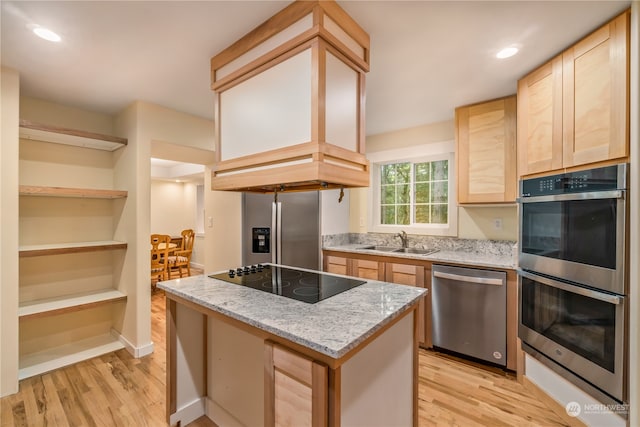 kitchen featuring light wood-type flooring, light stone counters, sink, a kitchen island, and appliances with stainless steel finishes