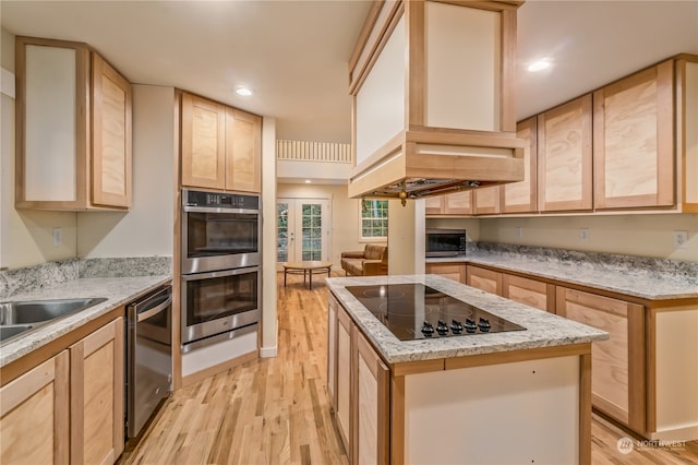 kitchen with light brown cabinetry, a center island, and stainless steel appliances