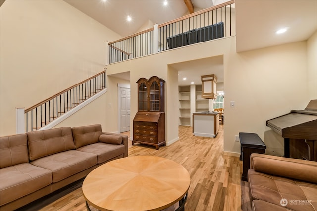 living room with high vaulted ceiling, beam ceiling, and light hardwood / wood-style floors