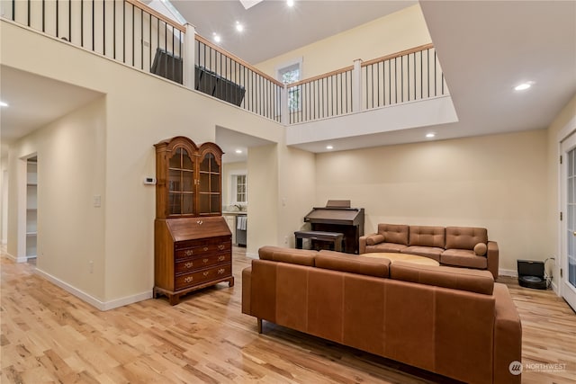 living room with light hardwood / wood-style floors and a towering ceiling