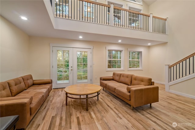 living room featuring light hardwood / wood-style flooring, a high ceiling, and french doors