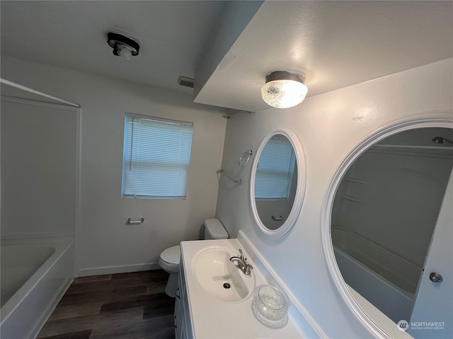 full bathroom with washtub / shower combination, toilet, hardwood / wood-style flooring, and vanity