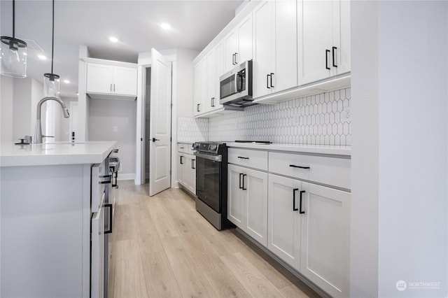 kitchen featuring sink, pendant lighting, range, light hardwood / wood-style floors, and white cabinetry