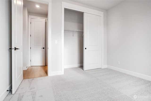 unfurnished bedroom featuring light colored carpet and a closet