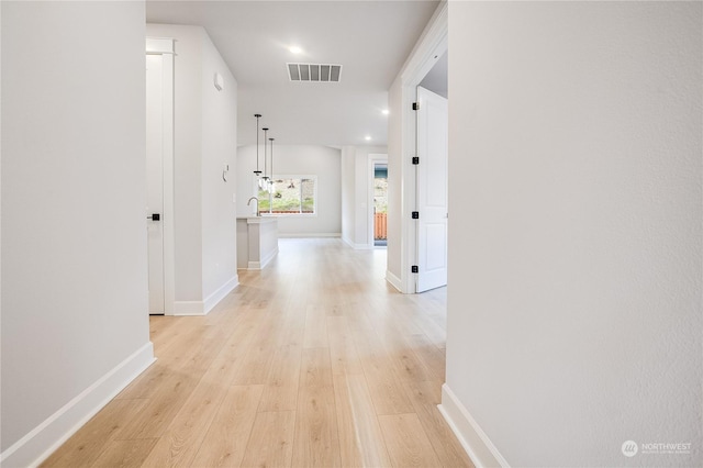 corridor featuring light wood-type flooring and sink