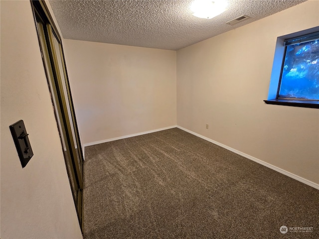 carpeted empty room featuring a textured ceiling