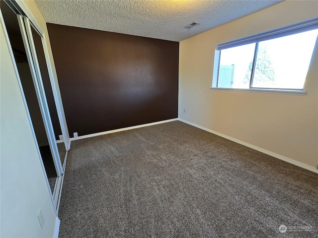 carpeted empty room with baseboards and a textured ceiling