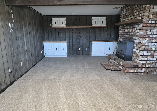 unfurnished living room with a wood stove, carpet flooring, and wood walls