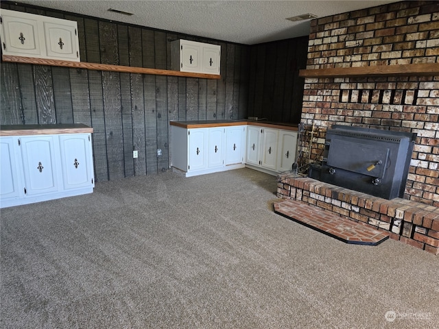 unfurnished living room featuring wood walls, carpet floors, and a brick fireplace