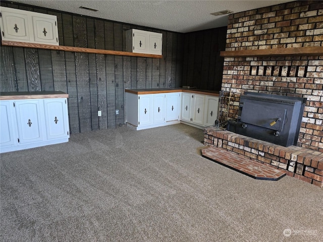 unfurnished living room featuring carpet flooring, a fireplace, a textured ceiling, and visible vents