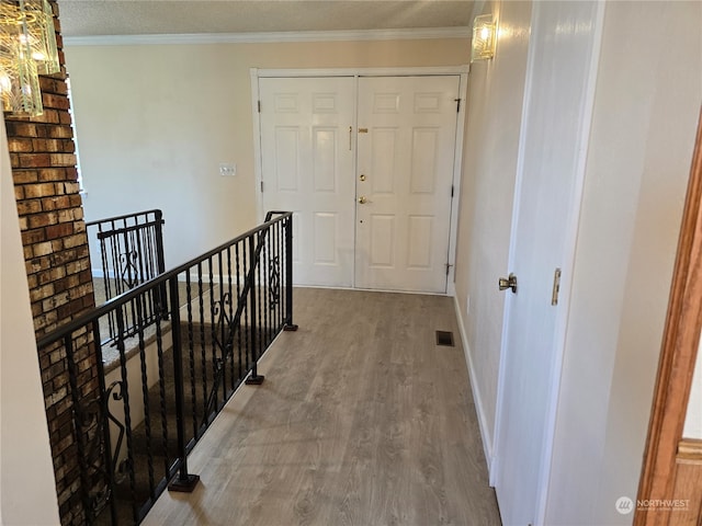 corridor featuring a textured ceiling, crown molding, and hardwood / wood-style floors