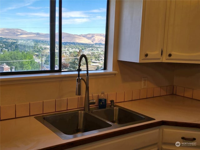 kitchen featuring light countertops, white cabinets, a mountain view, and a sink