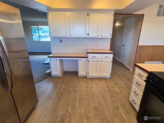 kitchen featuring visible vents, light wood finished floors, freestanding refrigerator, white cabinets, and range