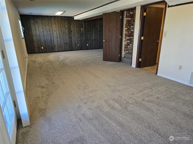 spare room with wood walls and light carpet