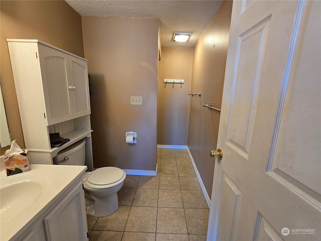 half bathroom with tile patterned flooring, baseboards, toilet, vanity, and a textured ceiling