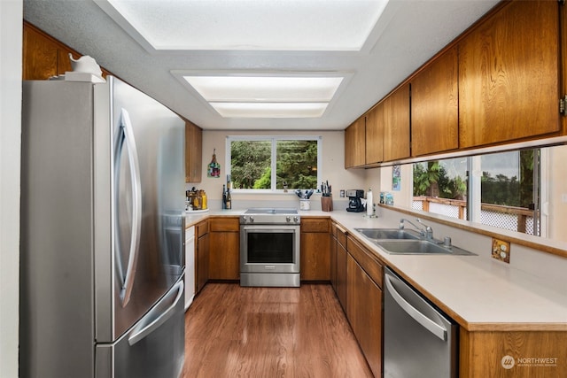 kitchen with stainless steel appliances, sink, and light hardwood / wood-style floors