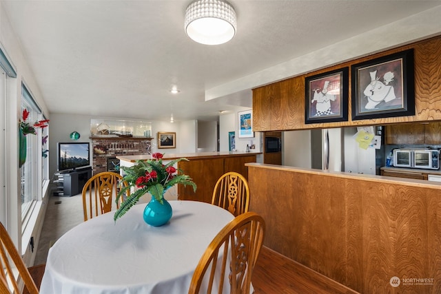 dining space with hardwood / wood-style floors and a brick fireplace