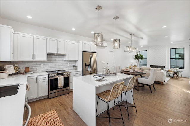 kitchen featuring white cabinets, hanging light fixtures, a center island, light hardwood / wood-style flooring, and stainless steel appliances