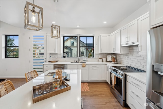 kitchen with light hardwood / wood-style flooring, appliances with stainless steel finishes, tasteful backsplash, hanging light fixtures, and white cabinetry