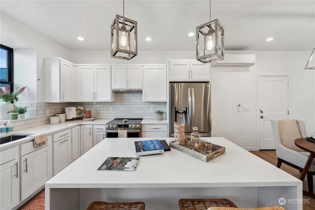 kitchen with white cabinets, hanging light fixtures, a center island, stainless steel appliances, and a wall mounted air conditioner