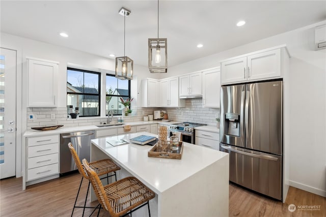 kitchen featuring a kitchen island, stainless steel appliances, white cabinets, and light hardwood / wood-style floors