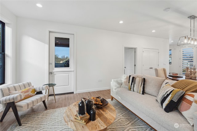 living room featuring plenty of natural light, light hardwood / wood-style flooring, and an inviting chandelier