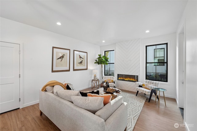 living room featuring light wood-type flooring, a healthy amount of sunlight, and a large fireplace