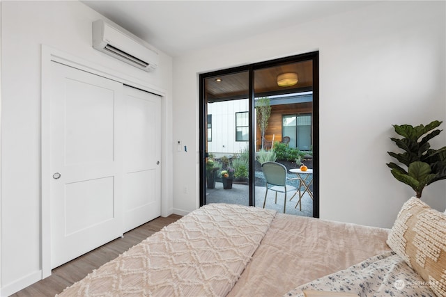 bedroom with a closet, a wall mounted air conditioner, dark hardwood / wood-style flooring, and access to outside