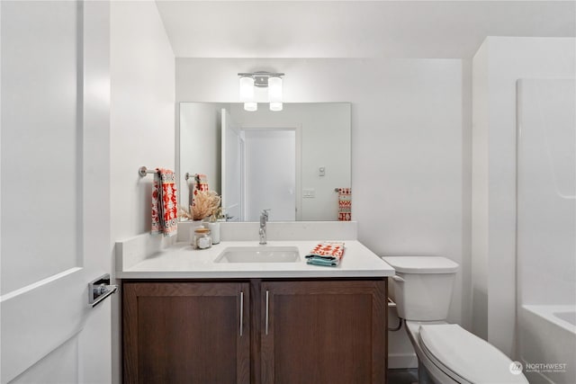 bathroom with a tub to relax in, vanity, and toilet