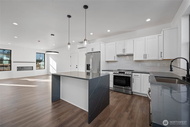 kitchen with white cabinetry, stainless steel appliances, a kitchen island, sink, and pendant lighting