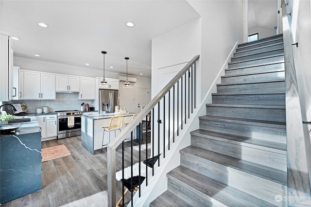 stairs featuring a wall mounted AC, hardwood / wood-style flooring, and sink