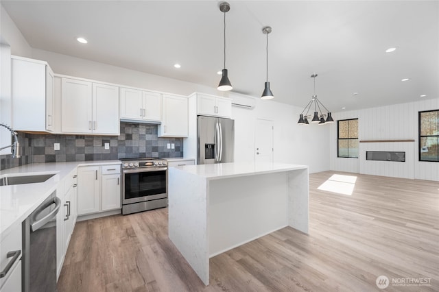 kitchen featuring white cabinetry, hanging light fixtures, stainless steel appliances, and a center island