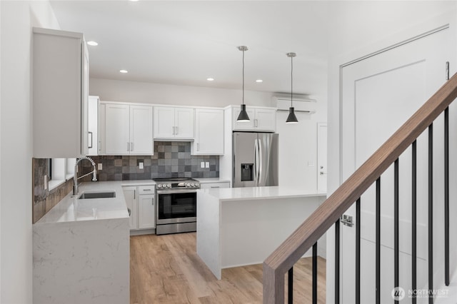 kitchen with white cabinetry, hanging light fixtures, sink, backsplash, and appliances with stainless steel finishes