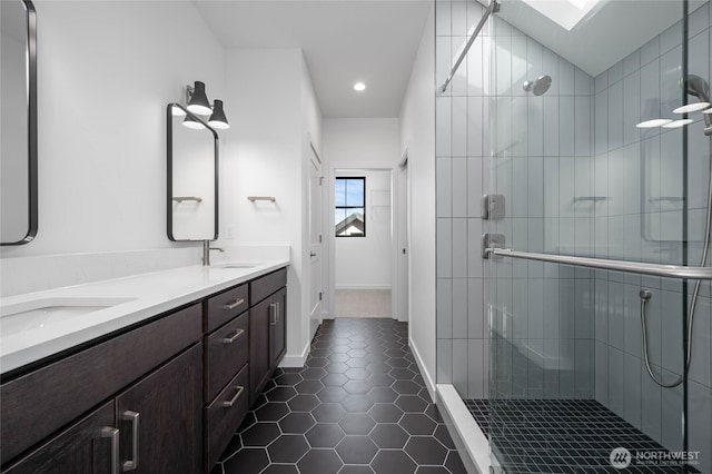 bathroom featuring vanity, a skylight, an enclosed shower, and tile patterned floors