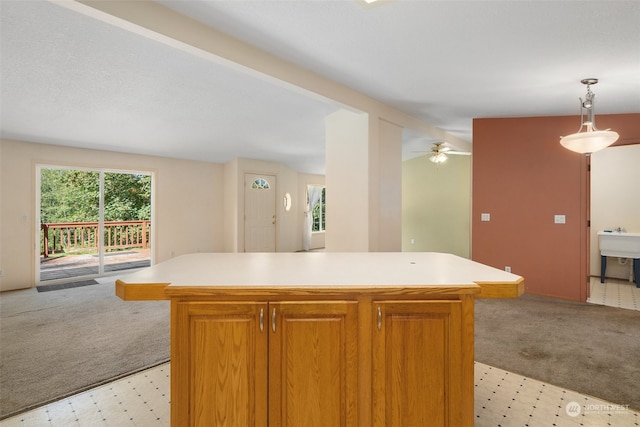 kitchen with light carpet, a center island, ceiling fan, and hanging light fixtures