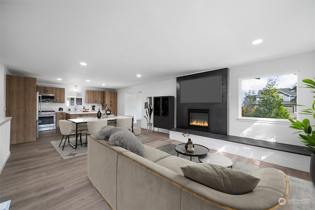 living room featuring light hardwood / wood-style flooring, sink, and a large fireplace