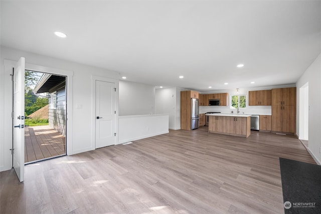 unfurnished living room with light wood-type flooring and sink