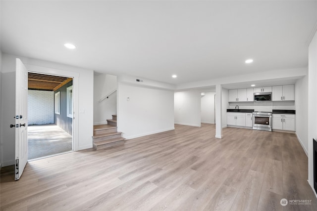 unfurnished living room with sink and light hardwood / wood-style flooring