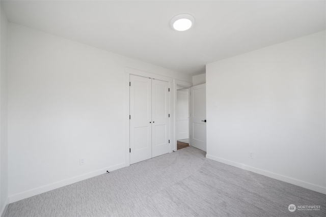 unfurnished bedroom featuring light colored carpet and a closet