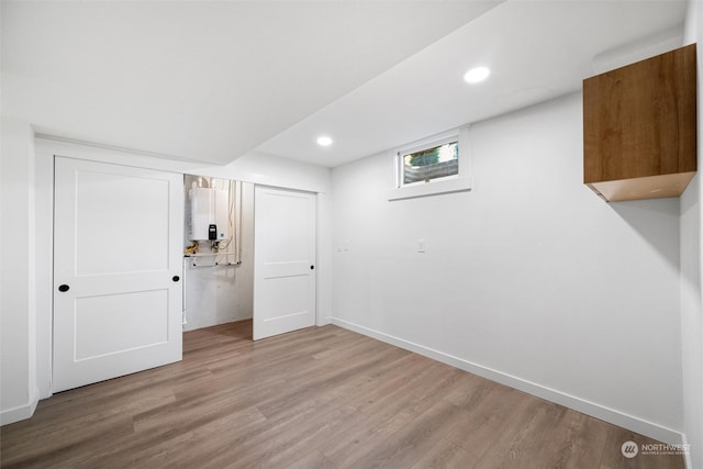 basement with wood-type flooring and tankless water heater