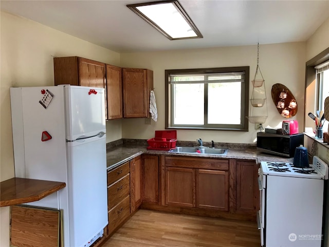 kitchen with white appliances, sink, and light hardwood / wood-style flooring