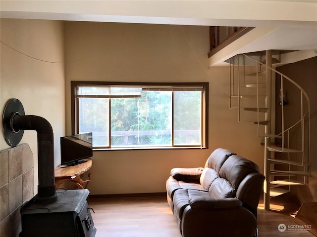 living area featuring wood finished floors, a wood stove, and baseboards