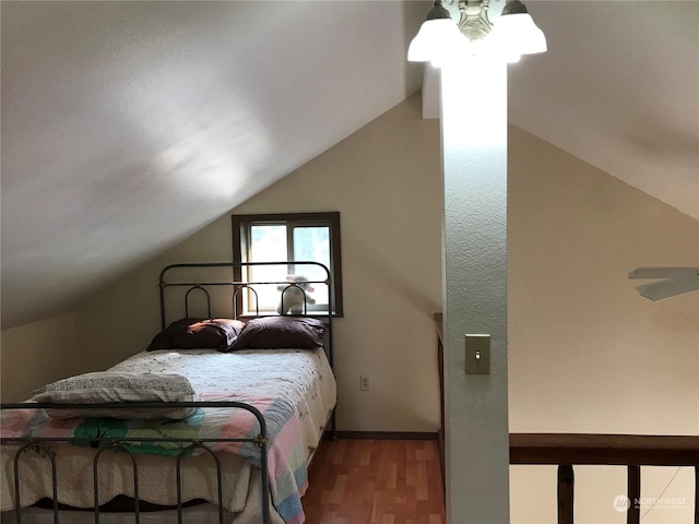 bedroom featuring baseboards, vaulted ceiling, and wood finished floors