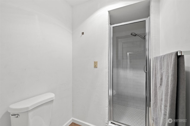 bathroom with a shower with door and toilet