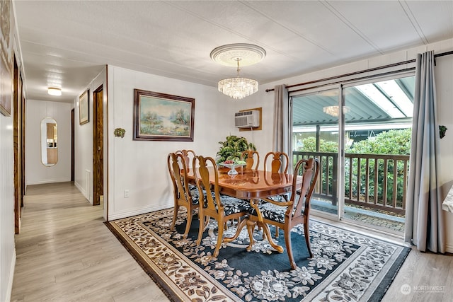 dining area with a textured ceiling, light hardwood / wood-style flooring, an AC wall unit, and a notable chandelier