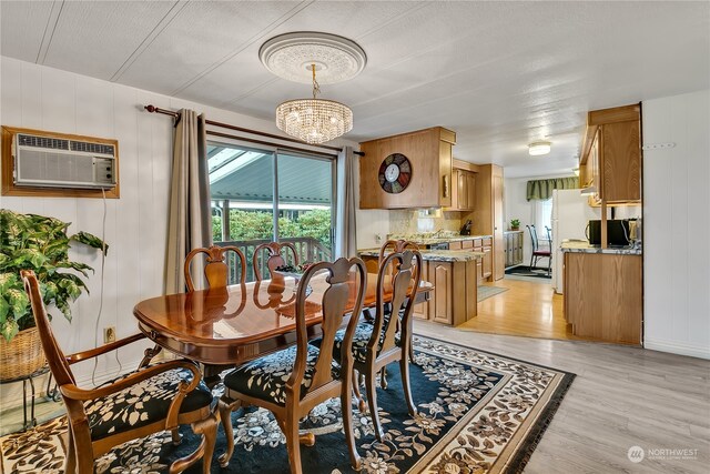 dining area featuring a textured ceiling, light hardwood / wood-style flooring, an AC wall unit, and a chandelier