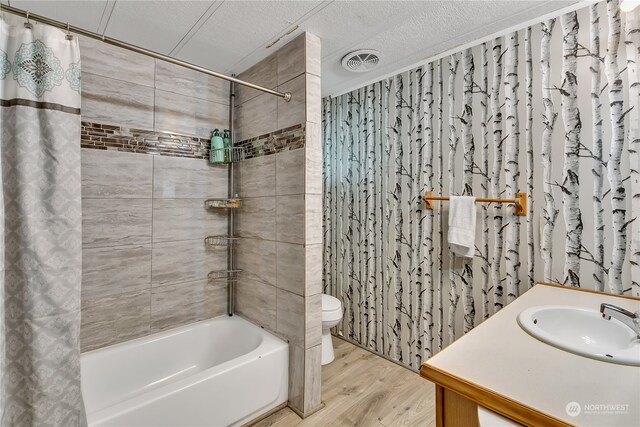 full bathroom with a textured ceiling, vanity, hardwood / wood-style floors, toilet, and shower / bathtub combination with curtain