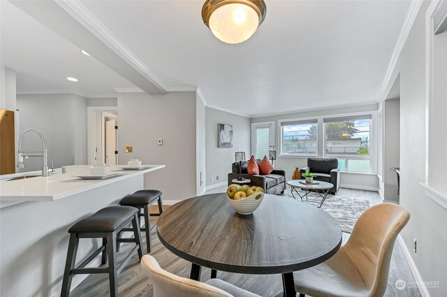 dining space with crown molding, wood-type flooring, and sink