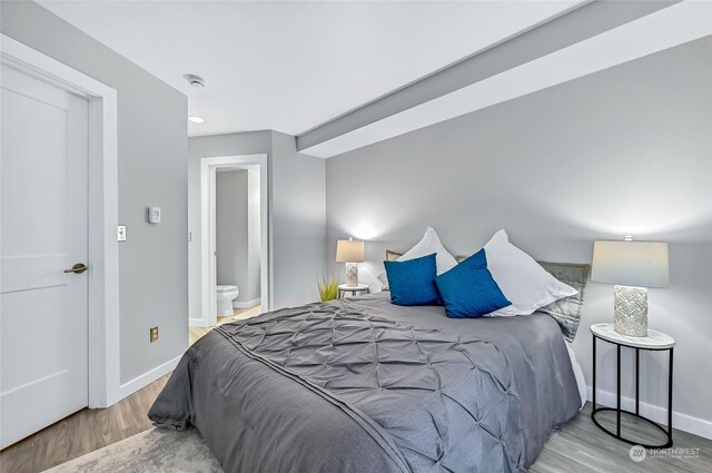 bedroom with light hardwood / wood-style floors and ensuite bathroom