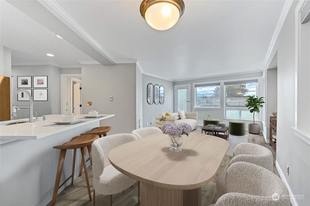 dining area featuring sink, crown molding, and light wood-type flooring